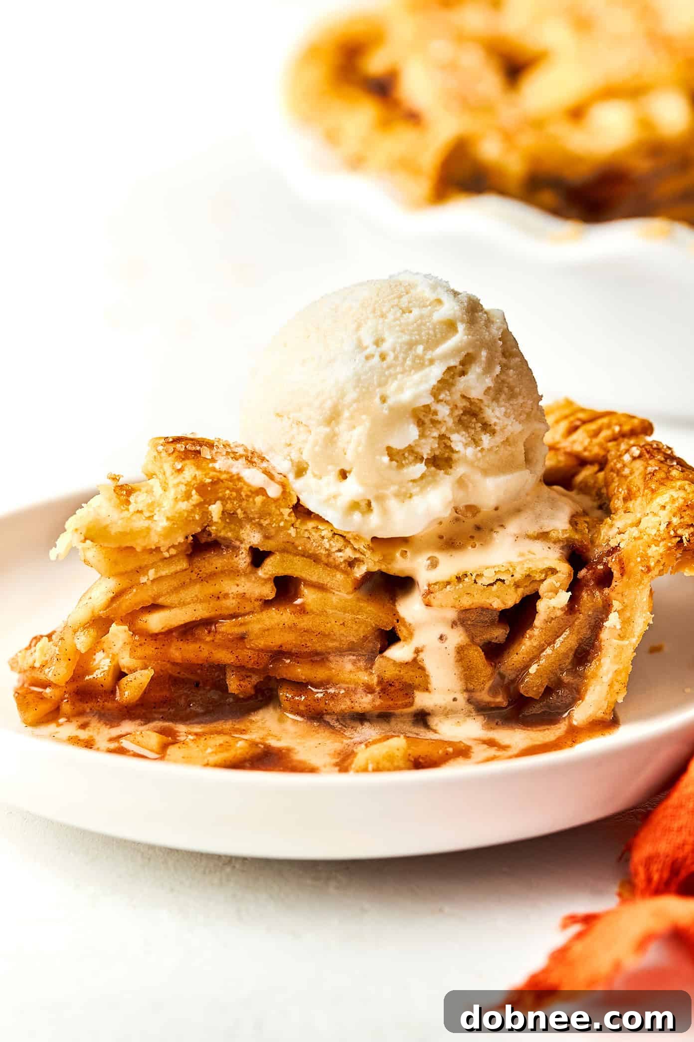 A perfectly baked slice of apple pie with a scoop of vanilla ice cream, ready to be enjoyed.