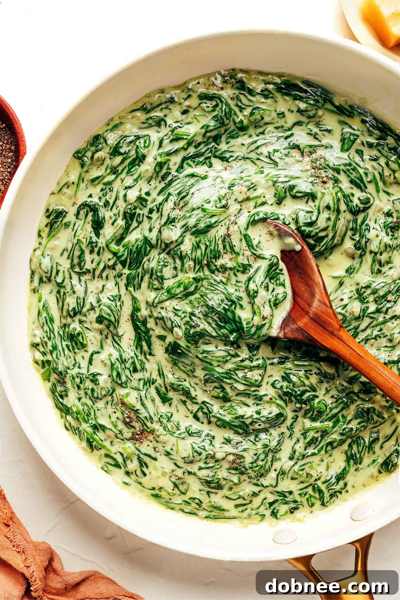 A vibrant bowl of creamy spinach, garnished with fresh parsley.