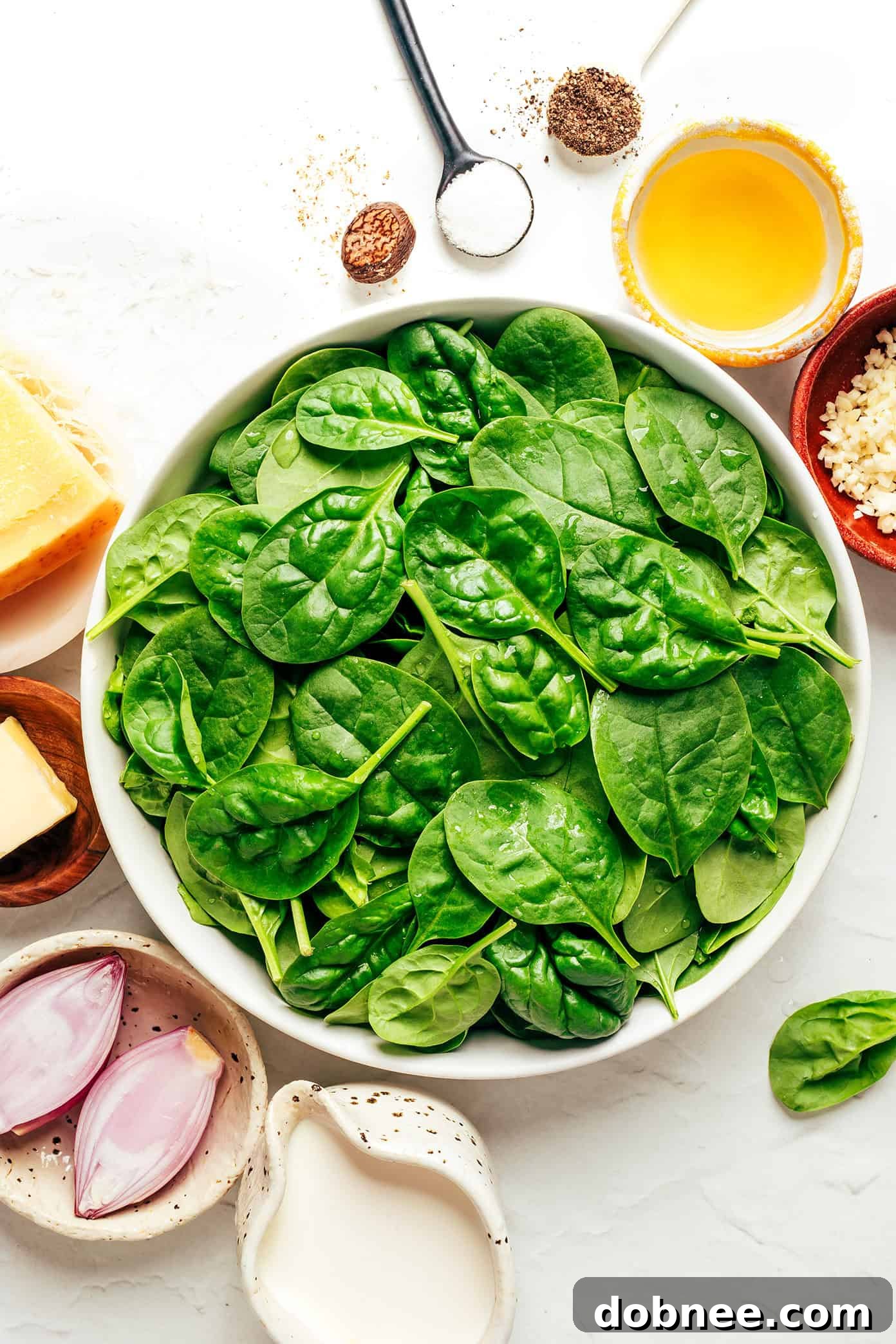 A large skillet filled with freshly wilted spinach and creamy sauce.