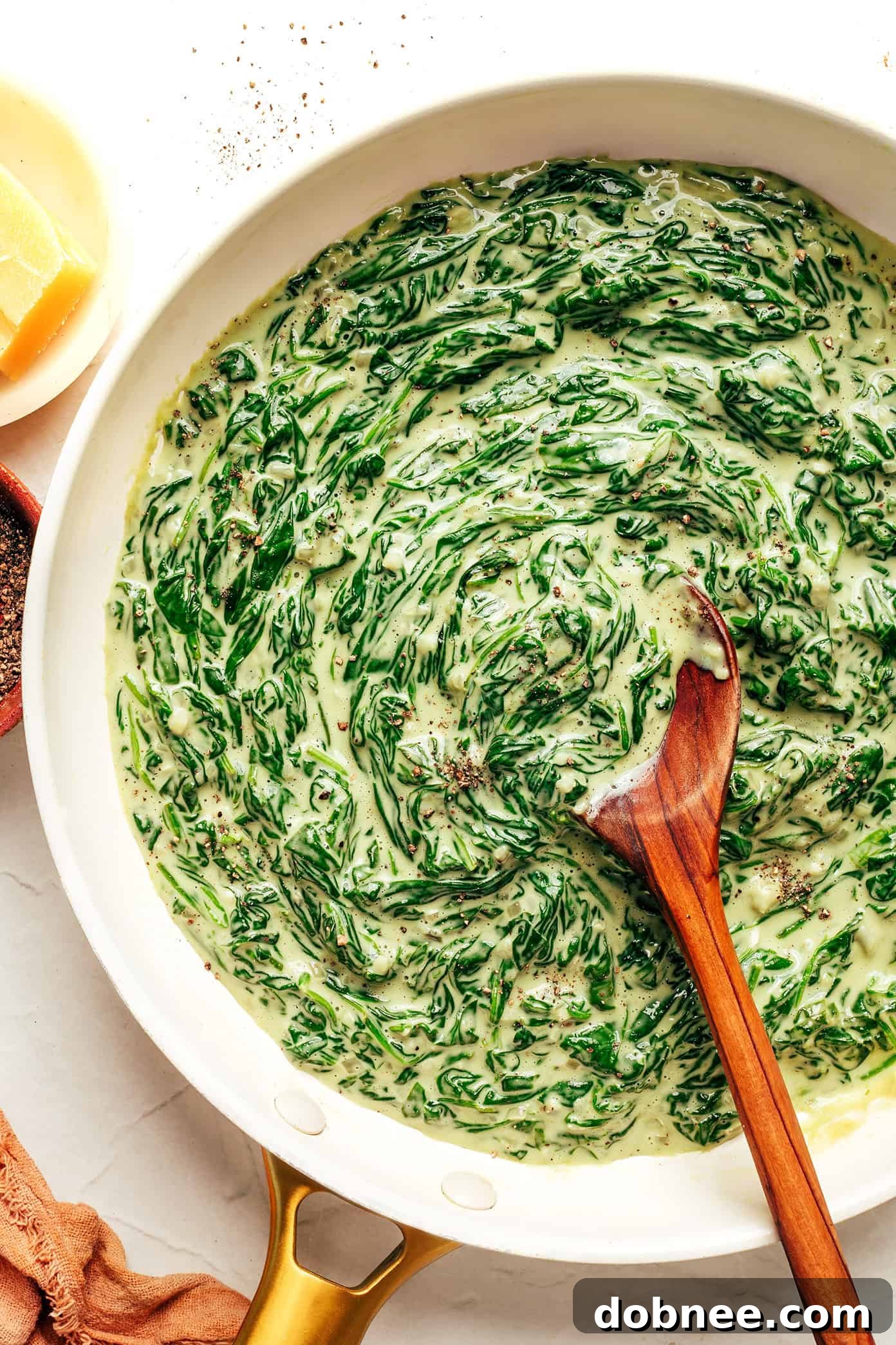 A serving of creamed spinach in a small white bowl, ready to be enjoyed.