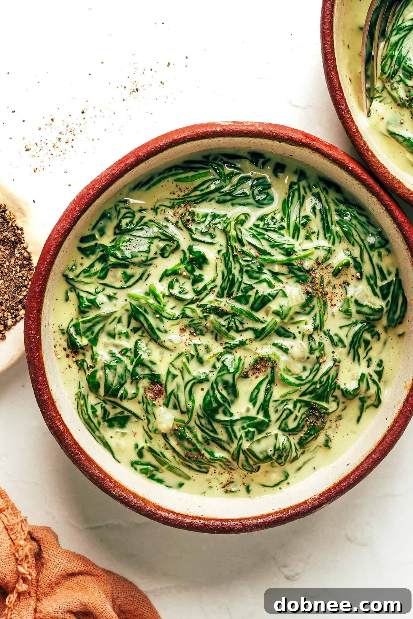 A dish of creamed spinach with a fork, ready to be eaten.