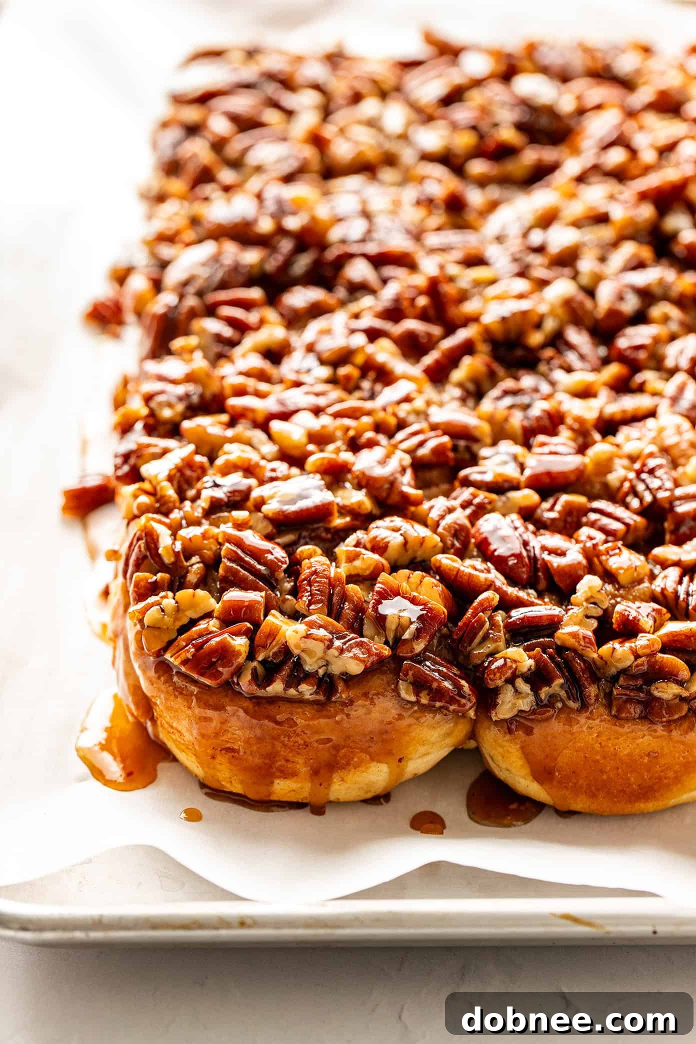A close-up shot of several golden, caramel-glazed sticky buns on a white platter, ready for serving