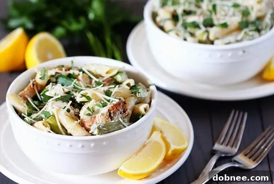 Delicious Lemon Rosemary Pasta with Chicken, Asparagus, and Spinach served in a white bowl, garnished with fresh rosemary.