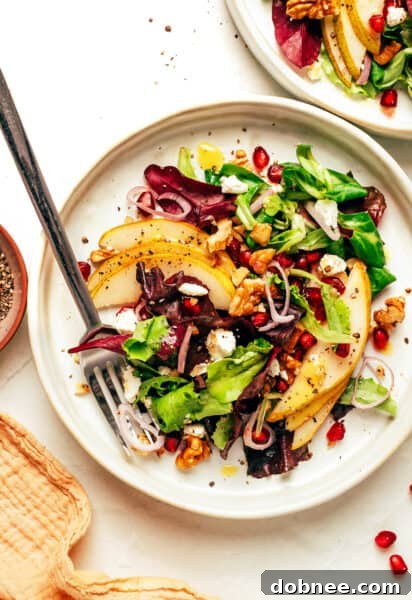 A beautifully arranged pear salad with goat cheese, walnuts, and pomegranate arils.