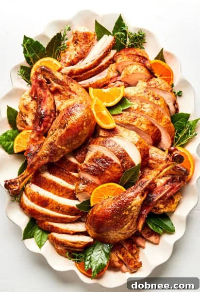 Carved roast turkey on platter with oranges and herbs
