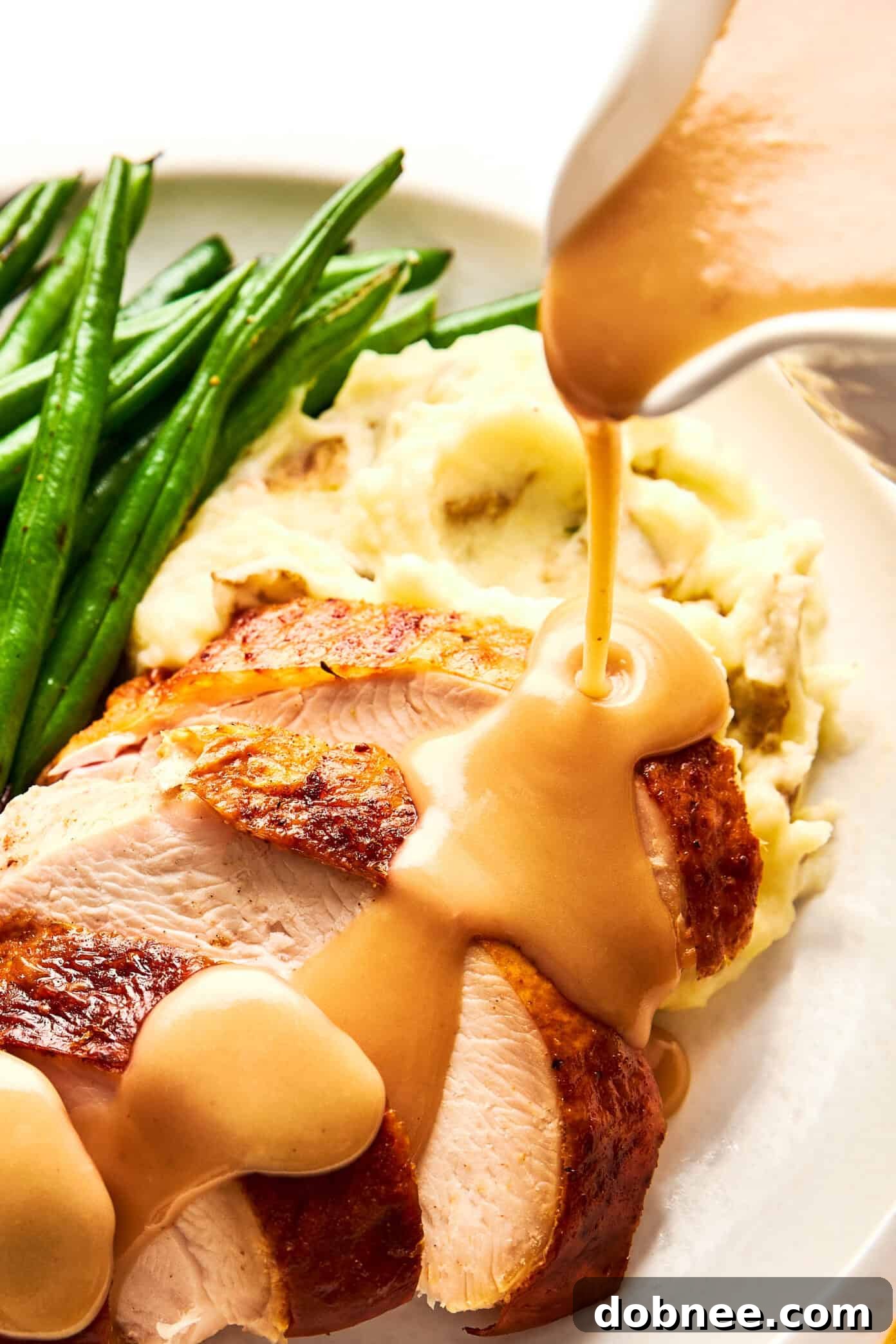 pouring turkey gravy over turkey and mashed potatoes