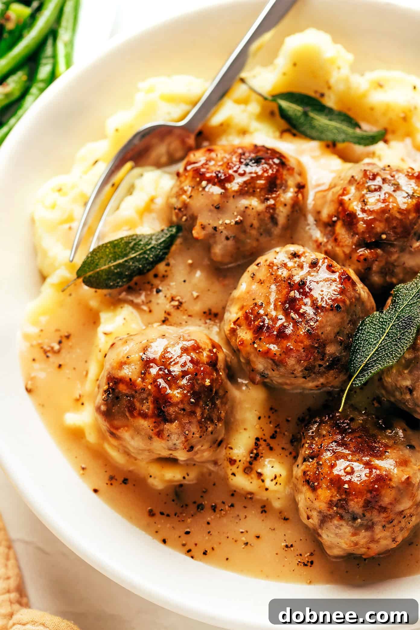 A full skillet of turkey meatballs and gravy, ready to be served, garnished with fresh herbs.