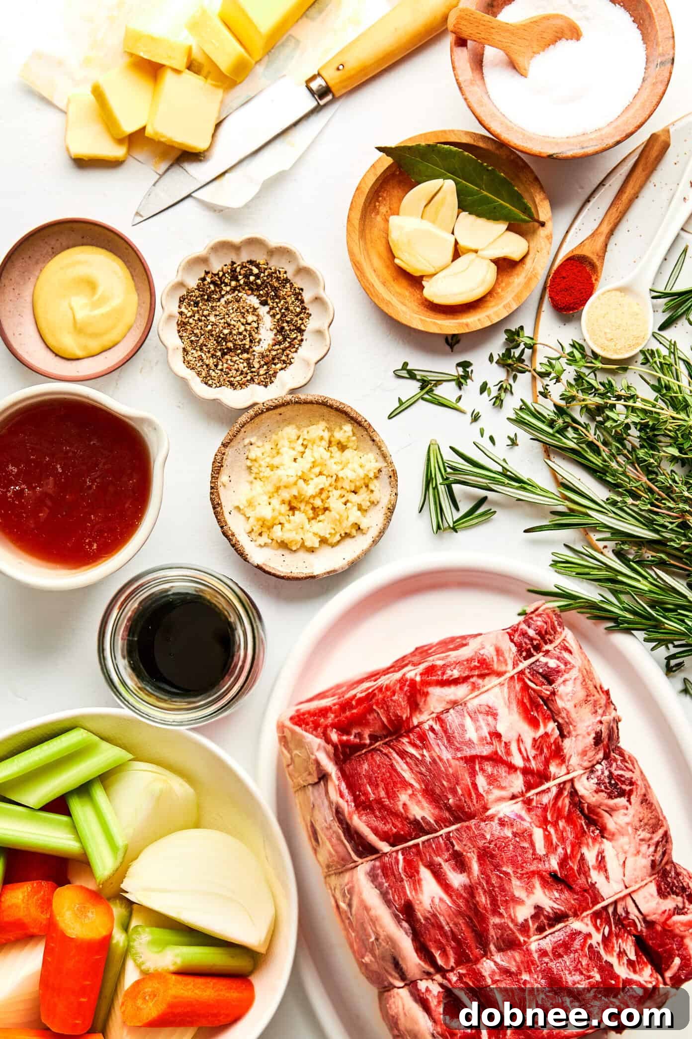 The seasoned prime rib roast, beautifully coated with garlic-herb butter, resting on a roasting rack with aromatic vegetables underneath.