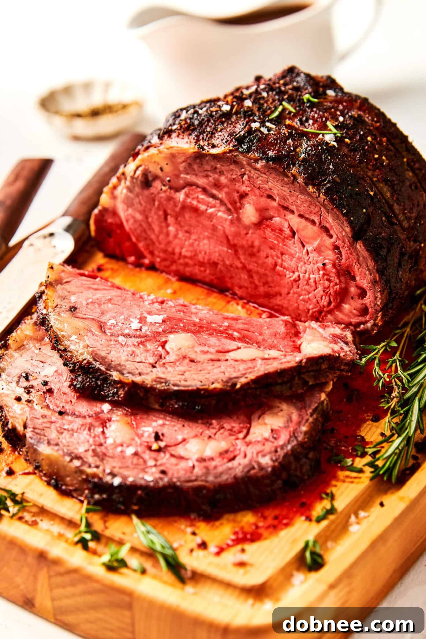 A delicate stream of rich, homemade au jus being poured from a gravy boat onto a serving platter.