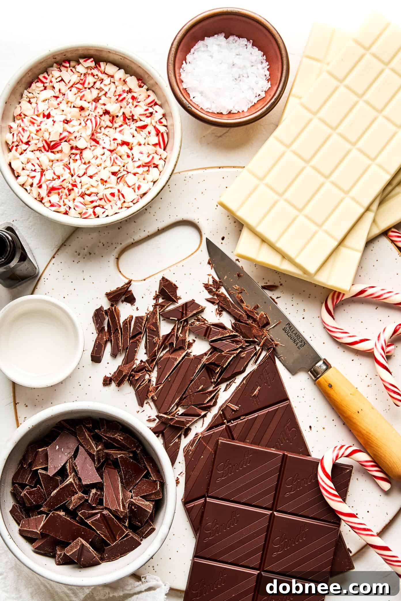 Festive Mint Chocolate Crunch 4 Ingredients laid out for making peppermint bark, including chocolate bars and candy canes.