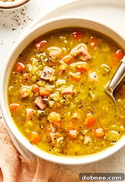 A bowl of split pea soup with ham on a rustic table.