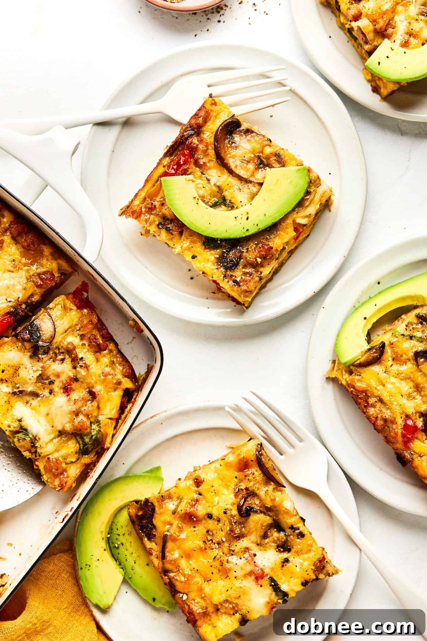 A serving of breakfast casserole, garnished with fresh green onions and avocado.