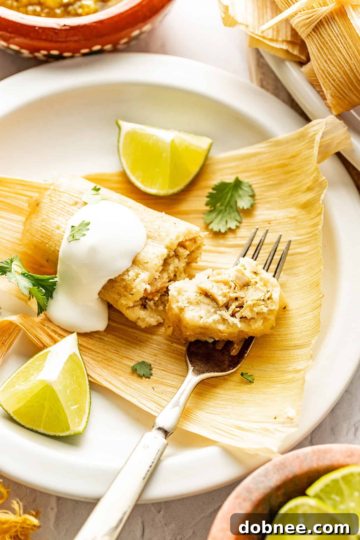 Green Chile Chicken Tamales 7 A close-up shot of a steamed green chicken tamale being unwrapped from its corn husk