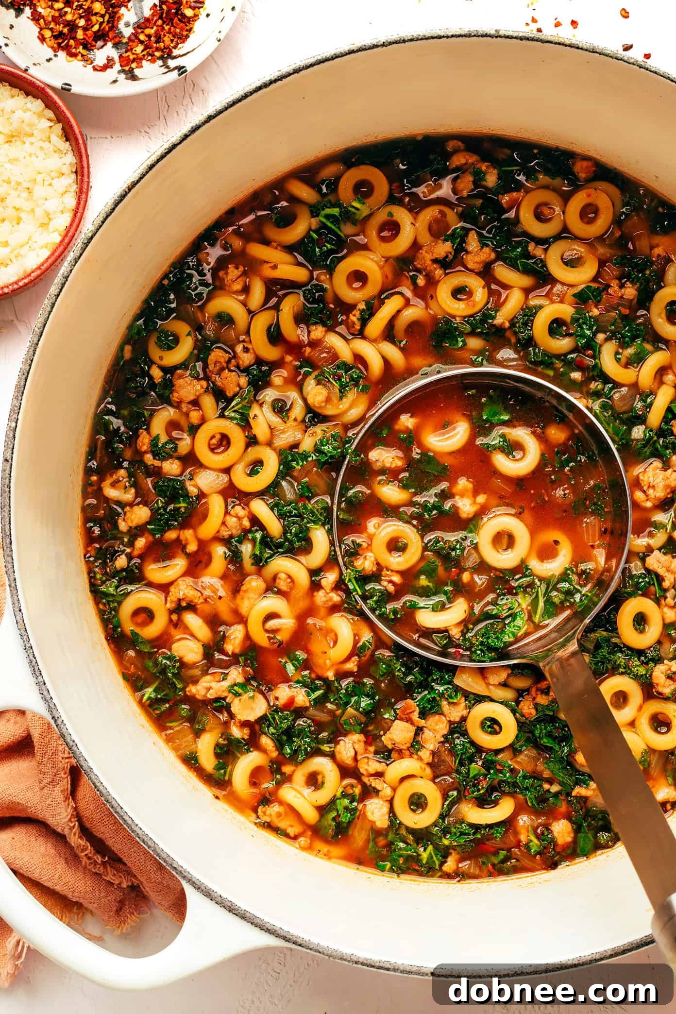 A comforting bowl of SpaghettiOs and Sausage Soup, garnished with fresh basil, on a rustic wooden table.