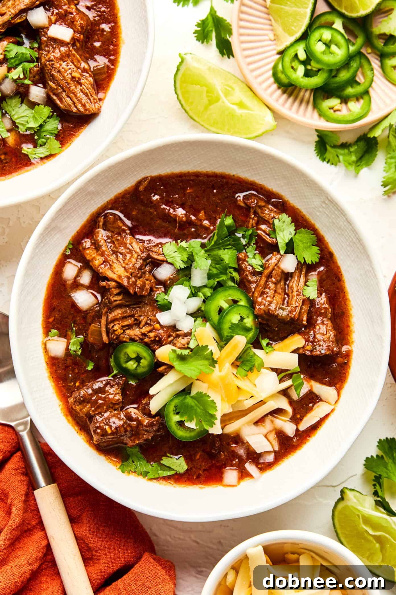 A steaming bowl of hearty Texas Chili, garnished with fresh cilantro and a lime wedge.