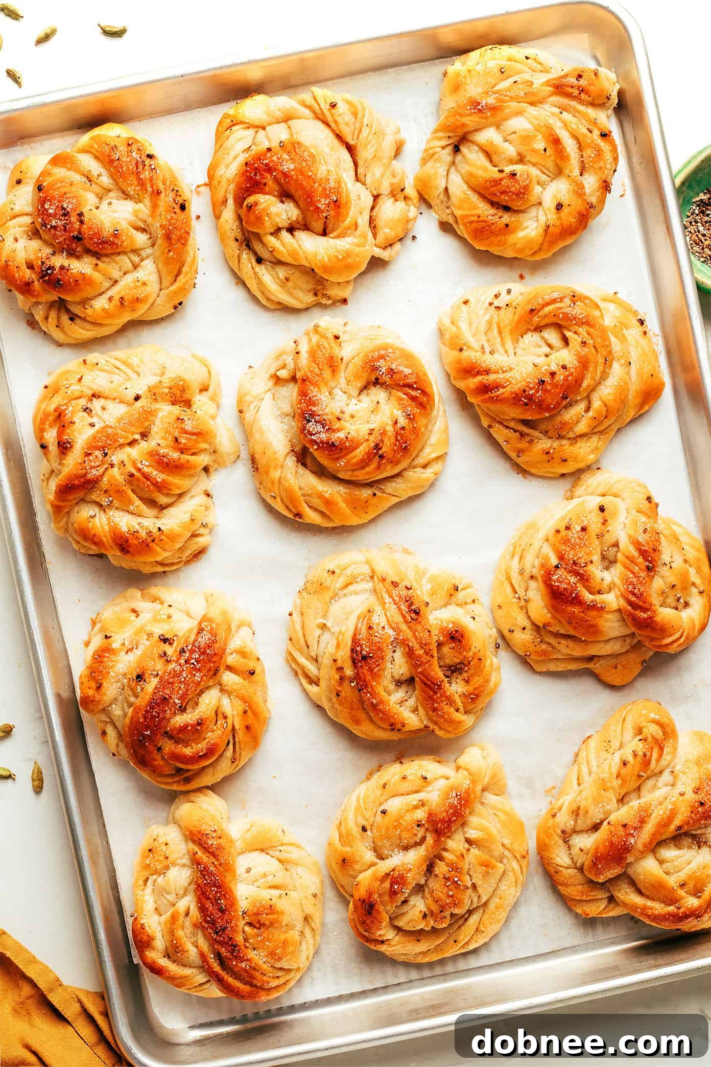 Several soft, golden Swedish Cardamom Buns arranged on a wooden board, ready to be enjoyed with coffee.