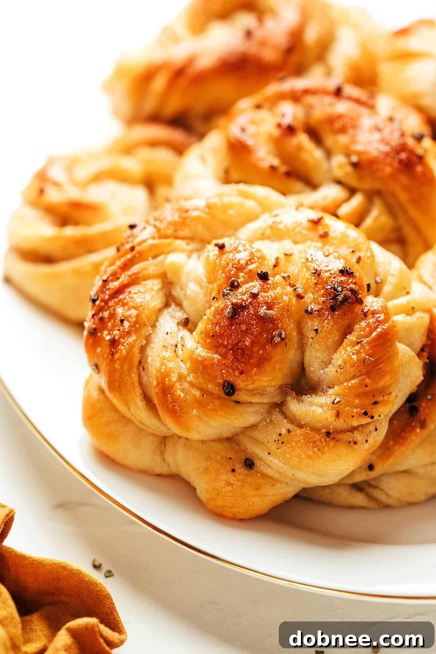 A beautifully composed shot of freshly baked cardamom buns, still on the baking sheet, glistening with syrup.