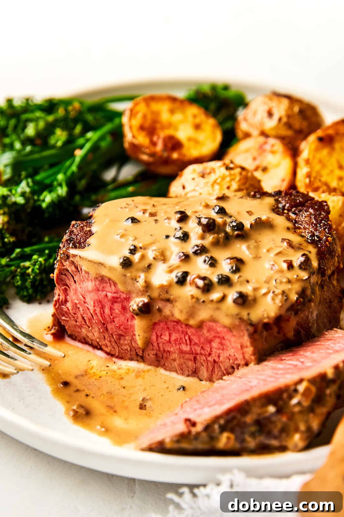 Close-up of seared filet mignon with peppercorn sauce, showcasing the perfect medium-rare center.