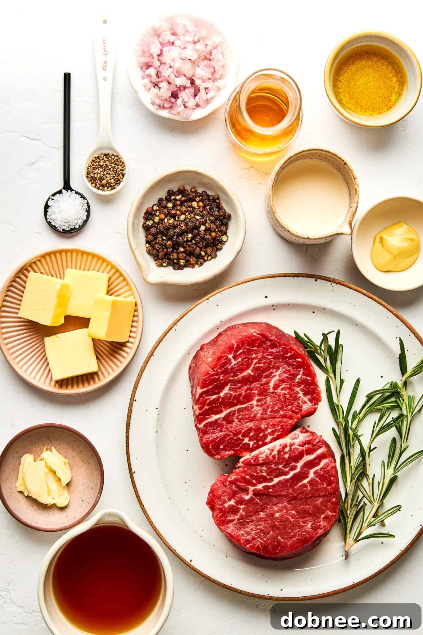 Ingredients for Filet Mignon with Peppercorn Sauce laid out on a wooden board.