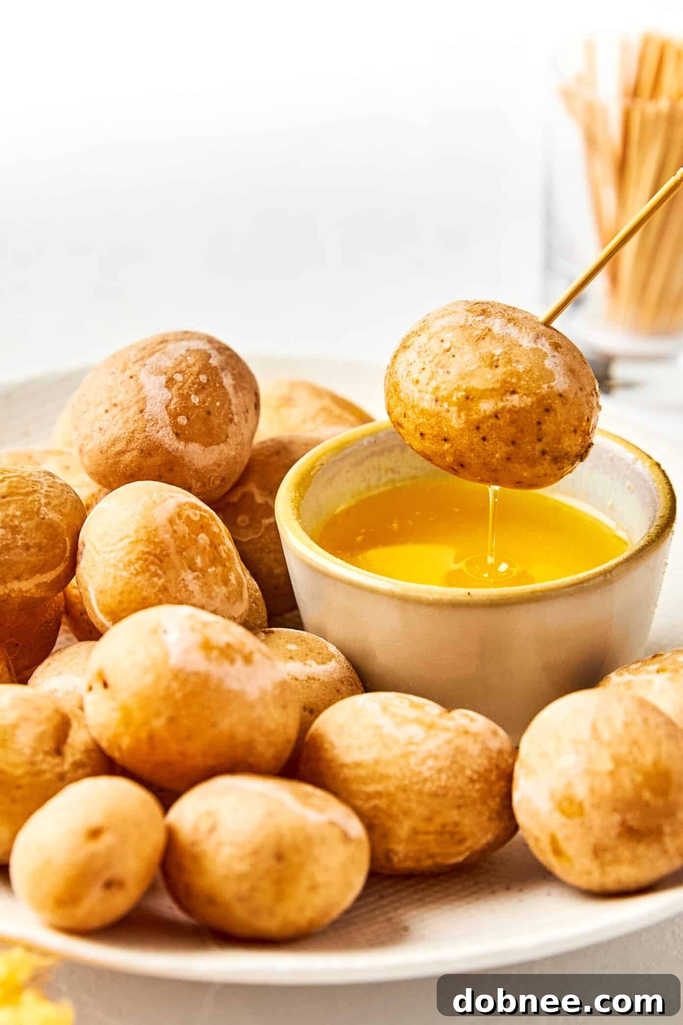 A rustic wooden spoon resting in a bowl of Syracuse Salt Potatoes with melted butter