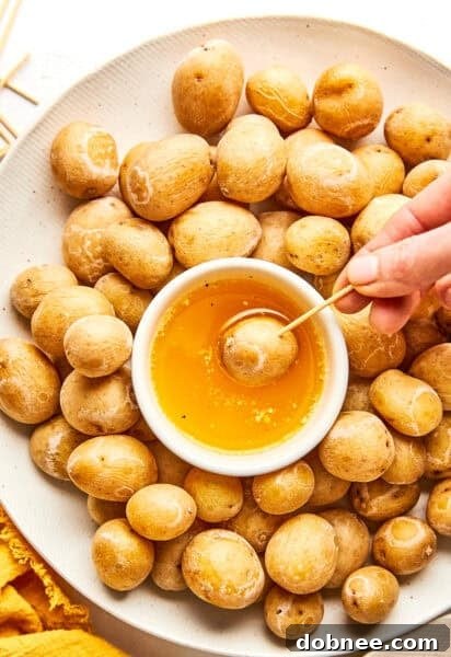 Syracuse Salt Potatoes served in a white bowl with a side of garlic butter for dipping.