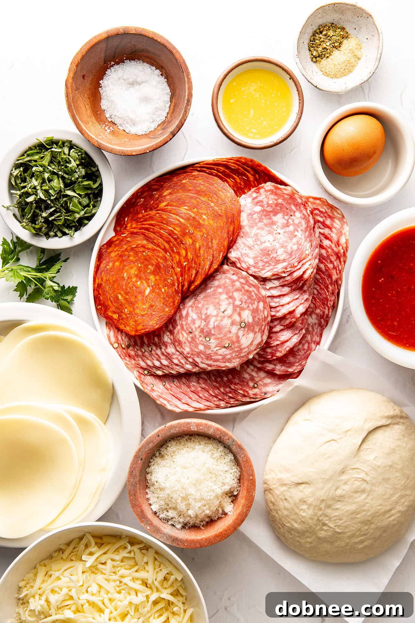 A vibrant display of fresh ingredients for Stromboli, including sliced meats, cheeses, and basil