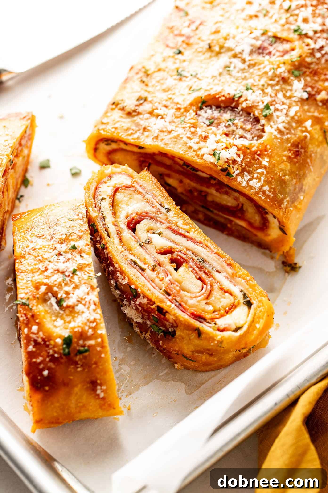 A cross-section of homemade Stromboli revealing layers of melted cheese and various Italian meats