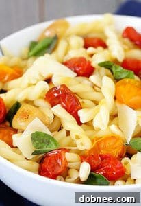 Close-up of pasta with slow-roasted tomatoes, garlic, and Parmesan, garnished with basil.