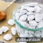 A small bowl of Biscoff Puppy Chow, ready to be eaten, showcasing its appealing texture and powdered sugar coating.