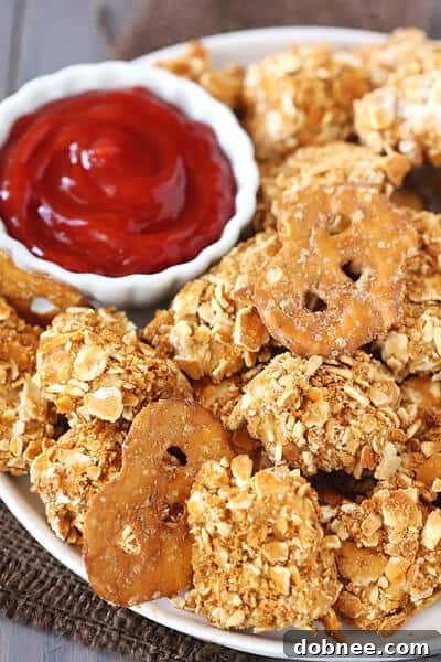 A close-up of golden brown Pretzel-Crusted Chicken Nuggets arranged on a plate, ready to be dipped.