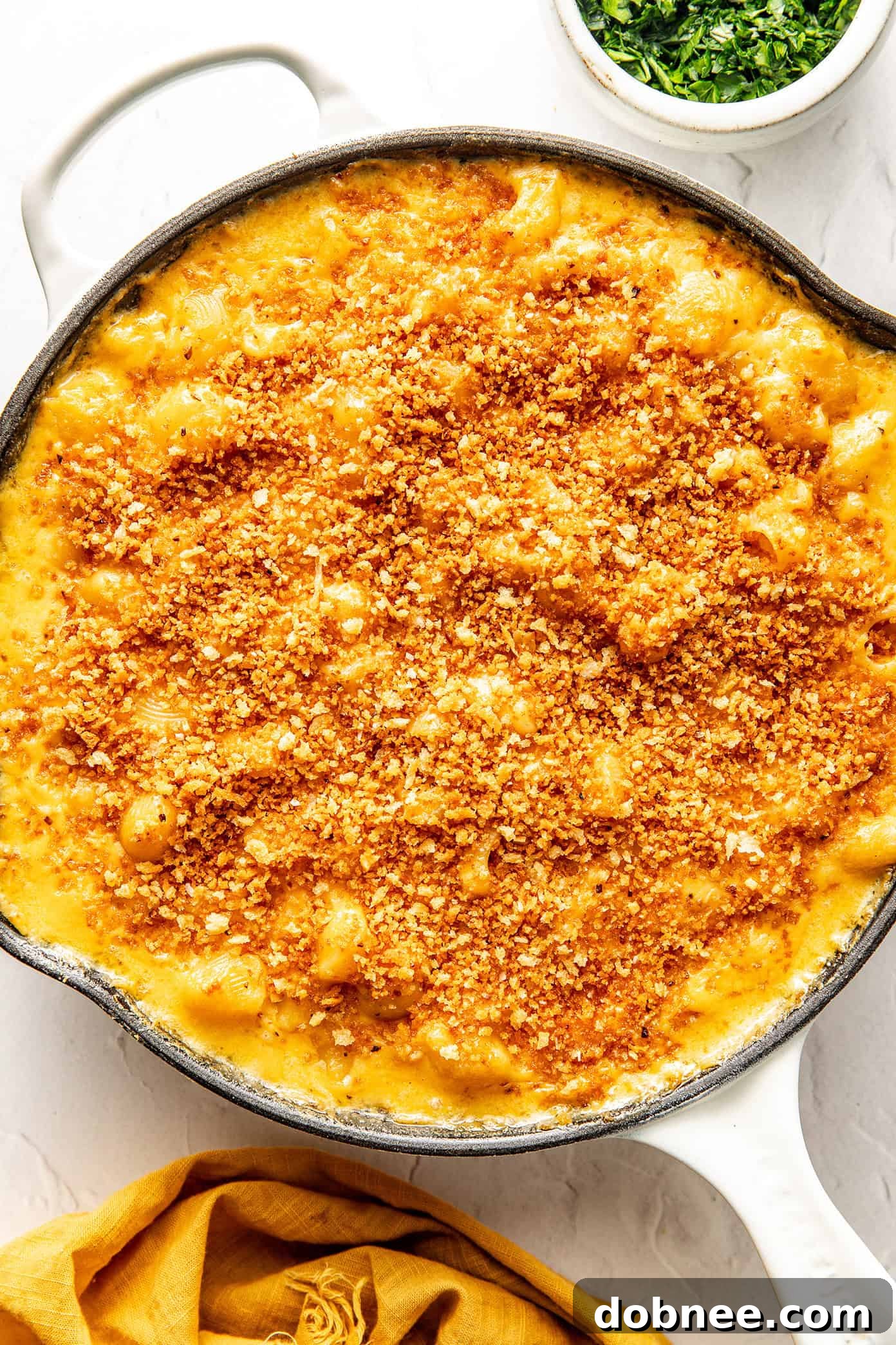 A pan of baked mac and cheese with a serving spoon.