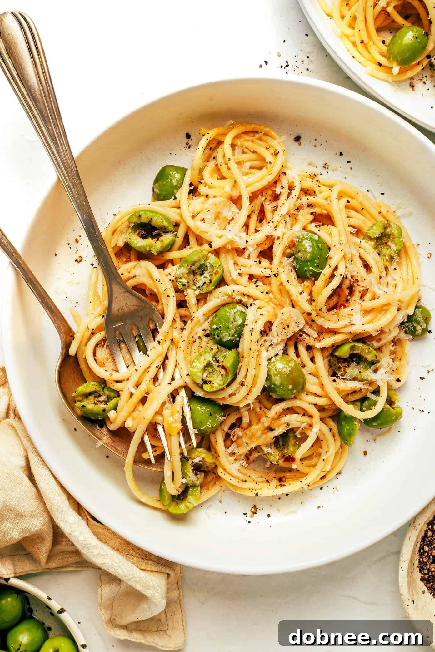 A serving of Dirty Martini Pasta with a fork, showing off its glossy sauce and olives.
